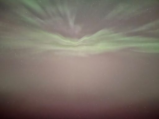 Overhead arc of green northern lights joining in the sky